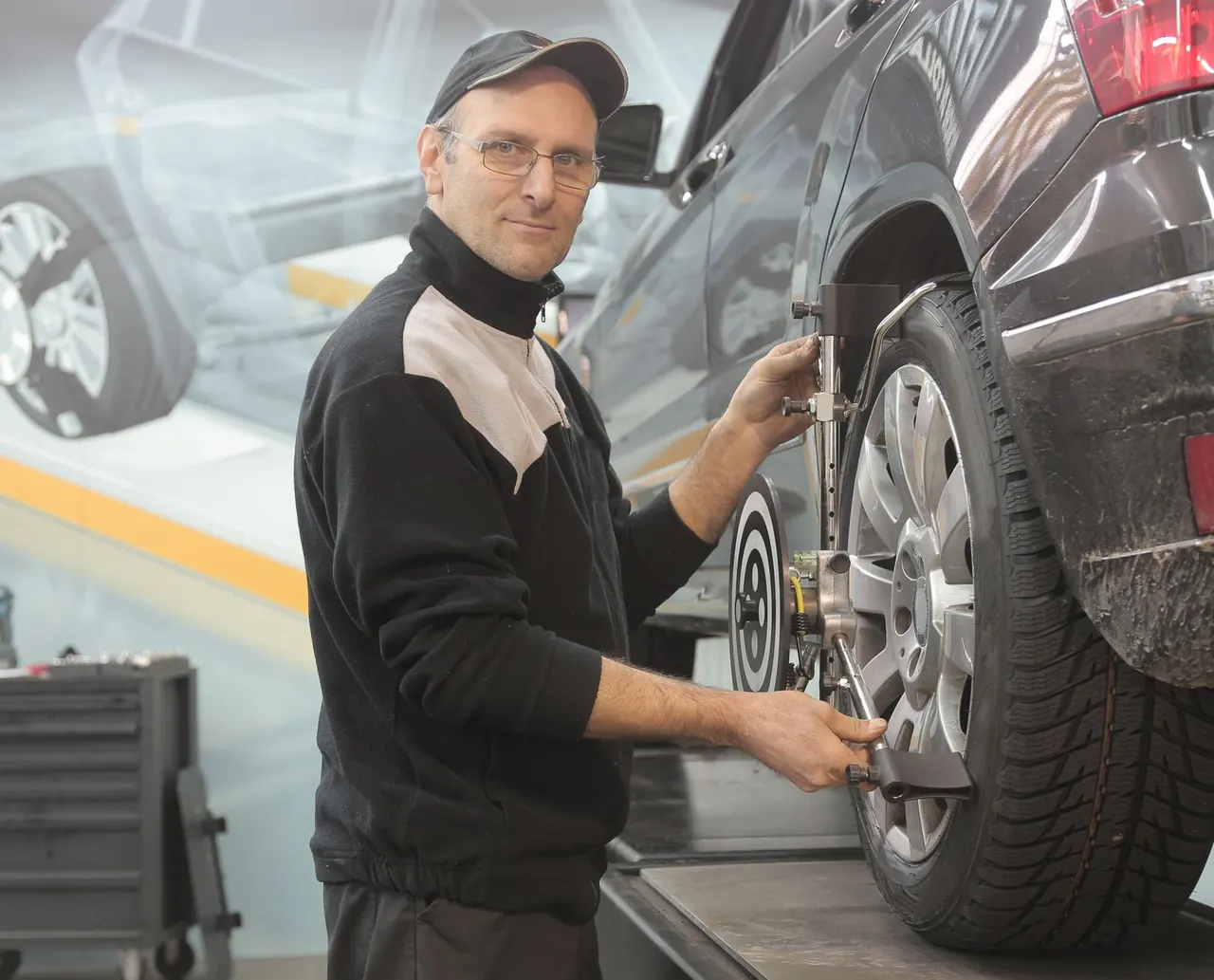 Technician fitting a wheel alignment measuring fixture.