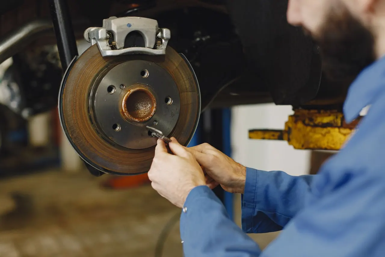 Mechanic inspecting a brake rotor with the wheel removed.