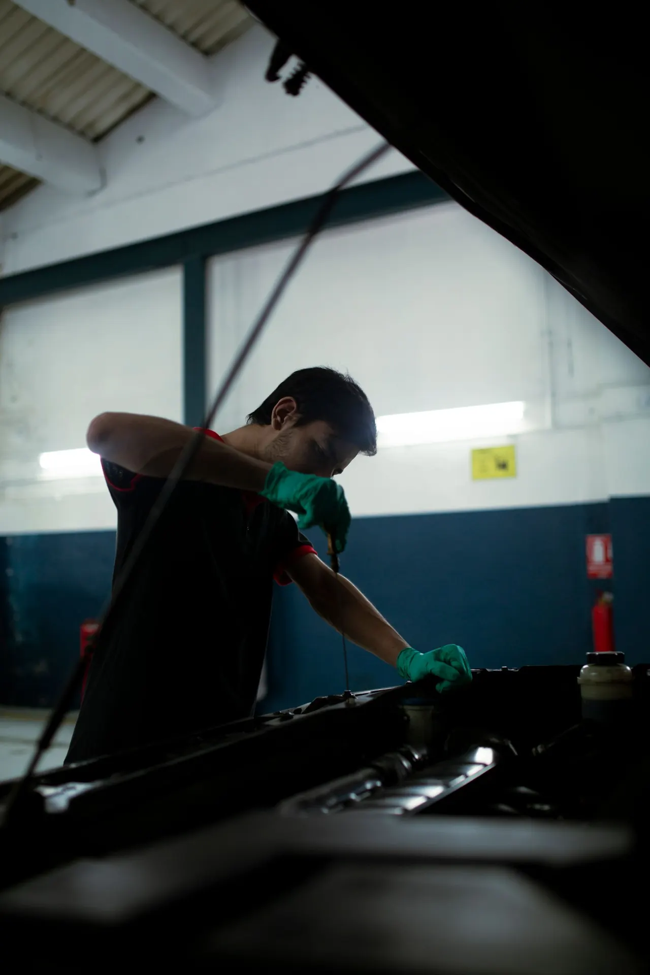 Mechanic checking engine oil with a dipstick in a garage.